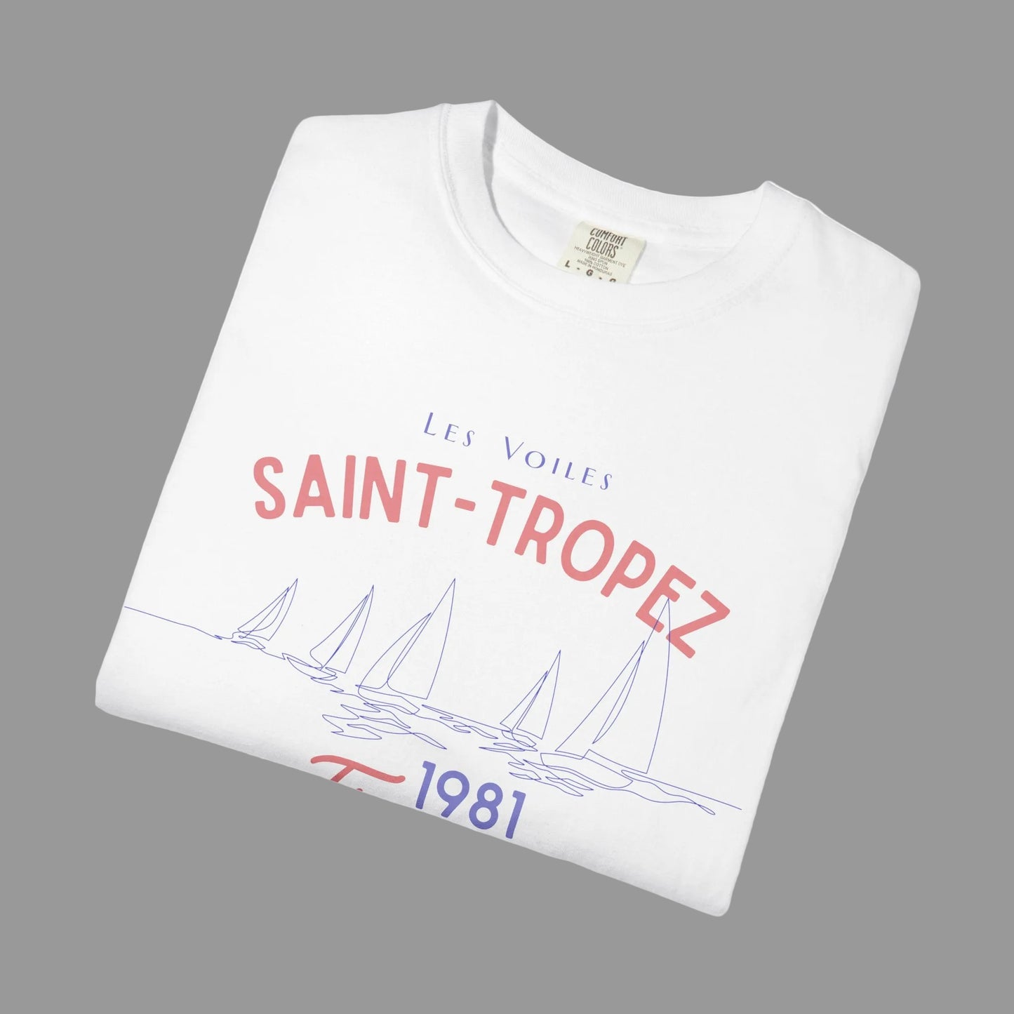 Folded white t-shirt with 'Saint-Tropez' text and sailboat design on a white background