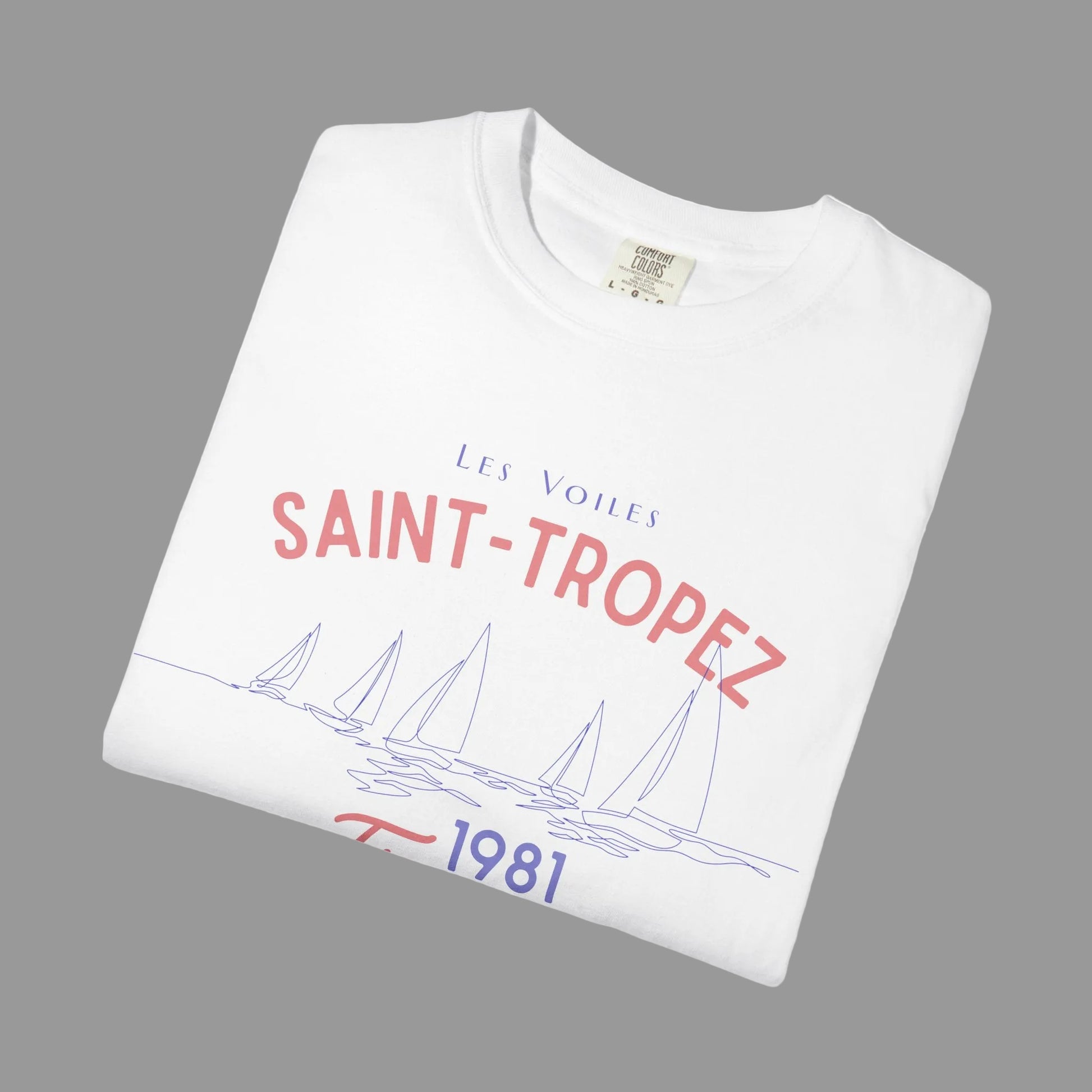 Folded white t-shirt with 'Saint-Tropez' text and sailboat design on a white background
